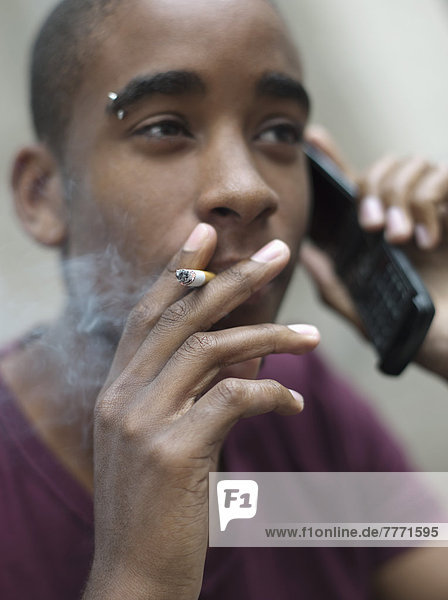 Teenage boy smoking while phoning