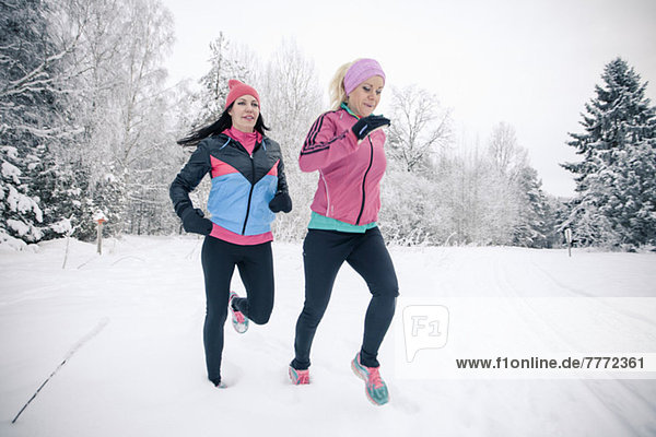 Mittlere erwachsene Freundinnen beim Joggen im Schnee
