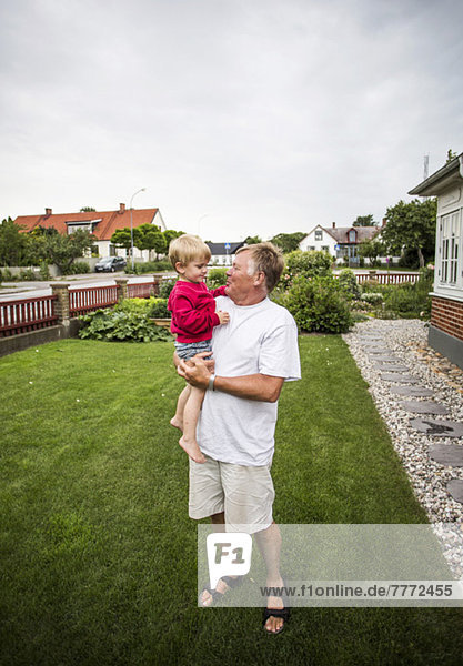 Glücklicher älterer Mann mit Enkel auf dem Rasen