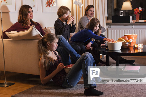 Fünfköpfige Familie beim gemeinsamen Fernsehen im Wohnzimmer