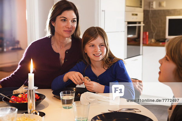 Glückliche Mutter mit Kindern beim Candlelight-Dinner zu Hause