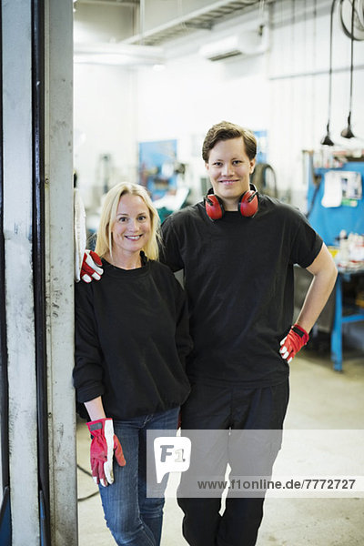 Porträt von selbstbewussten Mechanikern  die in der Kfz-Werkstatt zusammenstehen