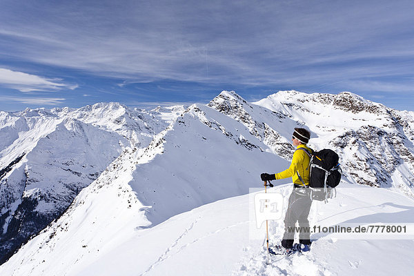 Cross-country skier on the summit of Ellesspitze Mountain in Pflerschtal valley  Hocheck Mountain at the rear
