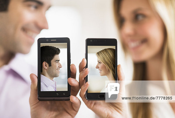 Couple holding smartphones with their pictures on