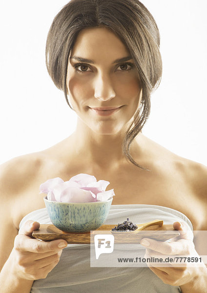 Woman holding tray with scented flower
