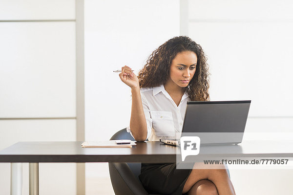 Office worker sitting by desk with laptop