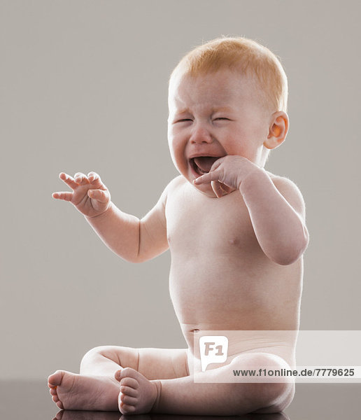 Studio shot of naked baby boy (18-23 months) crying