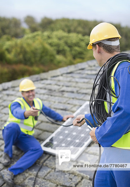 Arbeiter installieren Solarpanel auf dem Dach