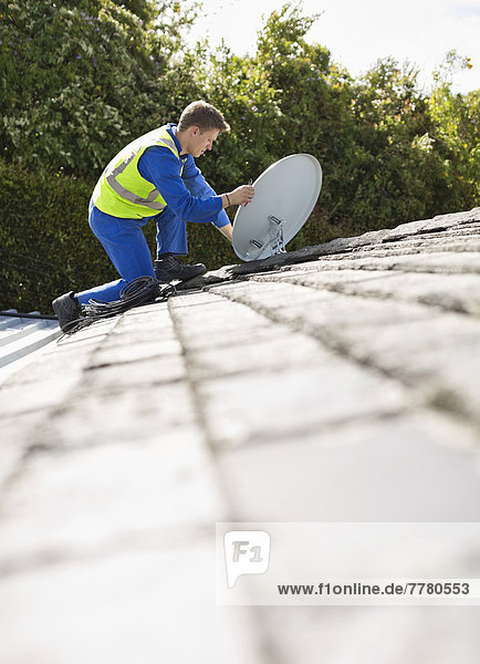Arbeiter installiert Satellitenschüssel auf dem Dach