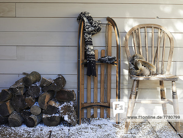 Schal  Holzschlitten  Stuhl und Brennholz auf der Veranda