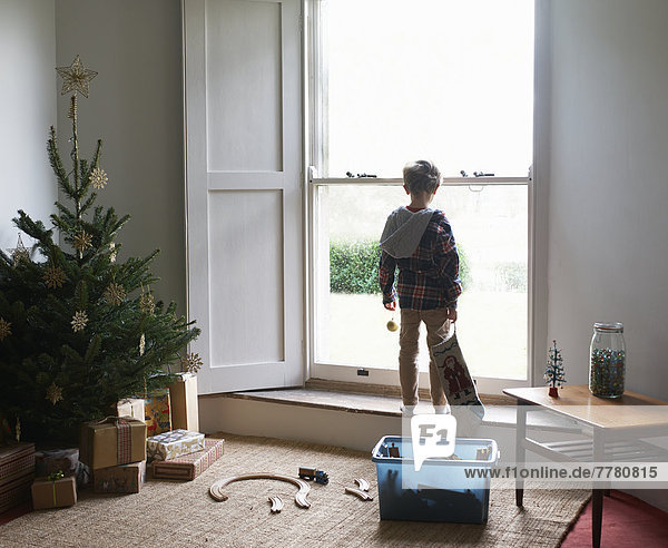 Junge mit Weihnachtsstrumpf am Fenster