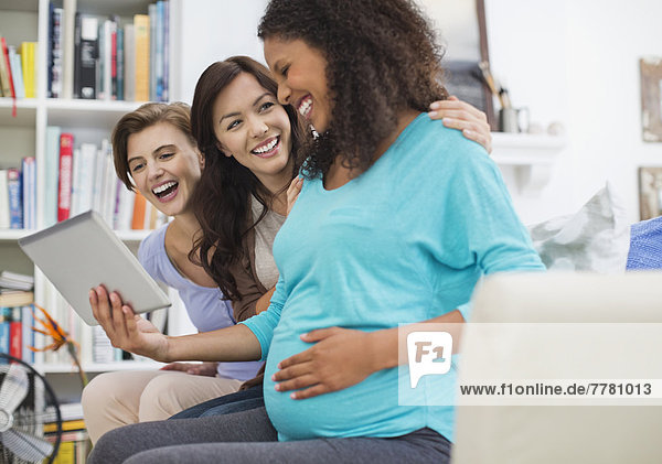 Schwangere Frau mit Tablet-Computer mit Freunden