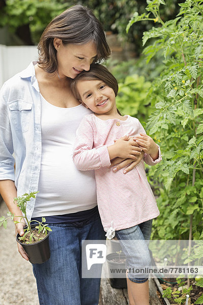 Schwangere Mutter und Tochter bei der gemeinsamen Gartenarbeit
