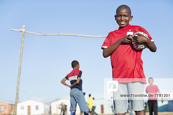 Junge hält Fußball im Dreckfeld