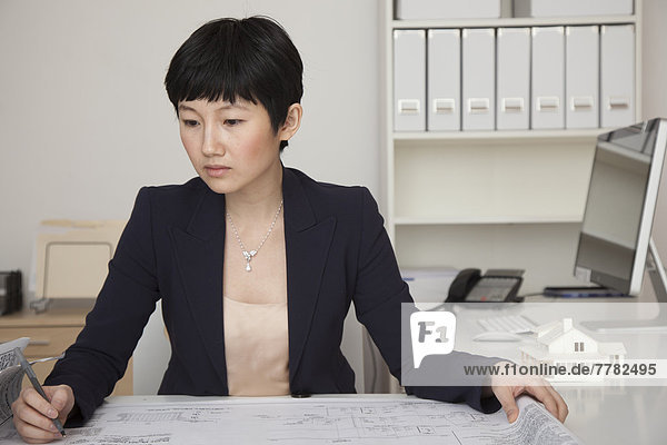 Businesswoman examining blueprints in office