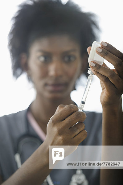 Black nurse filling syringe