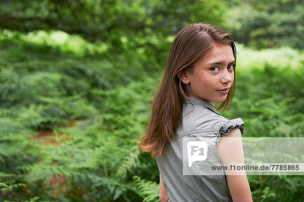 Teenage girl looking over shoulder in forest