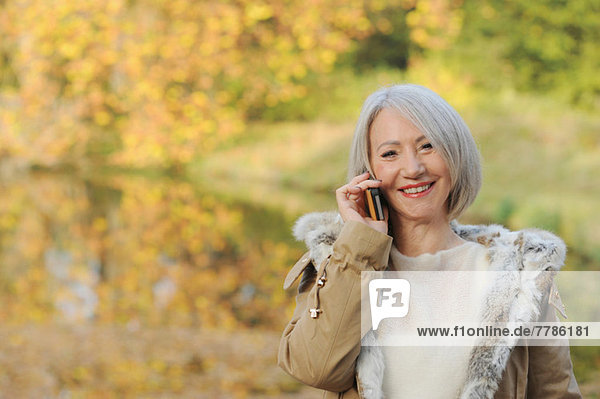 Porträt einer älteren Frau auf dem Handy im Freien