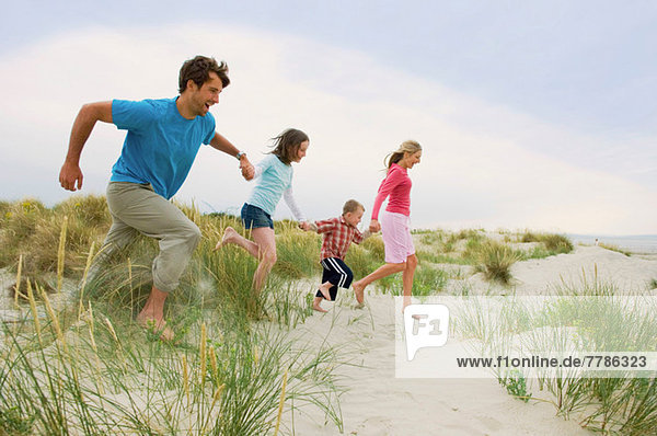Family holding hands and running at the beach
