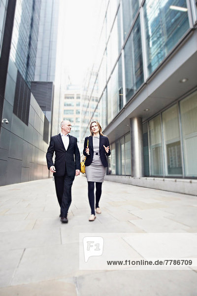 Businessman and businesswoman walking past office buildings