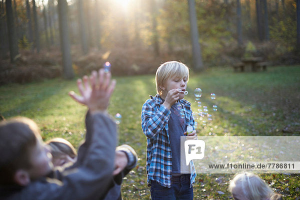 Kinder spielen mit Blasen im Wald