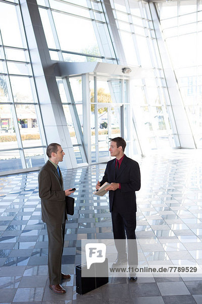 Two businessmen in lobby with briefcase