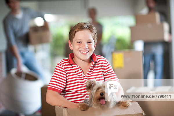 Boy moving house with dog in box