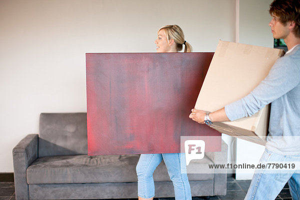 Junges Ehepaar beim Umzug mit Kiste und Malerei
