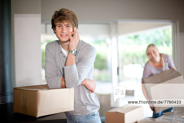 Young man moving house on cell phone