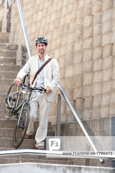 Junger Mann auf einer Treppe mit Fahrrad