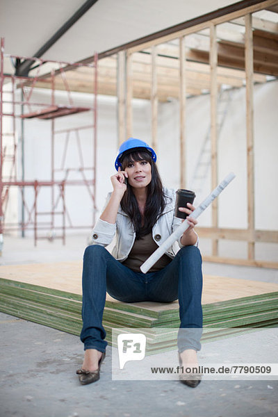 Portrait of woman holding blueprint on cell phone