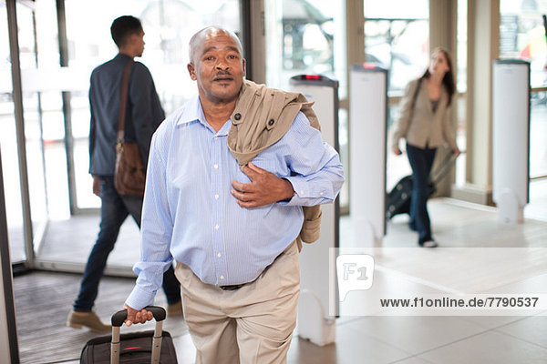 Senior im Flughafen mit Koffer