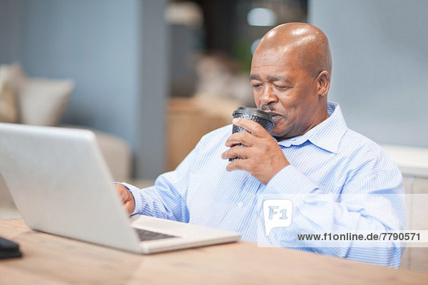 Geschäftsmann trinkt Kaffee mit Laptop