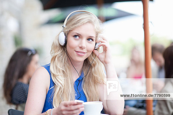 Junge Frau im Café mit Kopfhörern