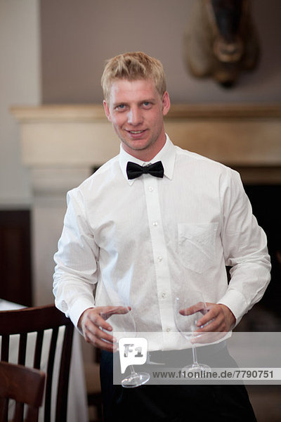 Waiter holding empty wine glasses in restaurant