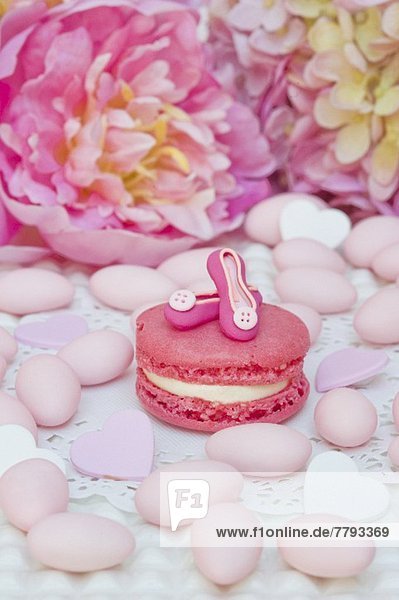 Pink Macaron mit handgemachten Pumps  umgeben von Zuckermandeln  Dragees und Pfingstrosen