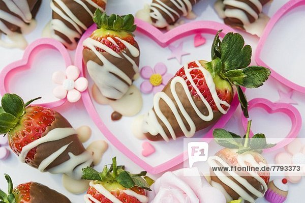 Schokoladenerdbeeren in rosa Herzen mit Zuckerblumen