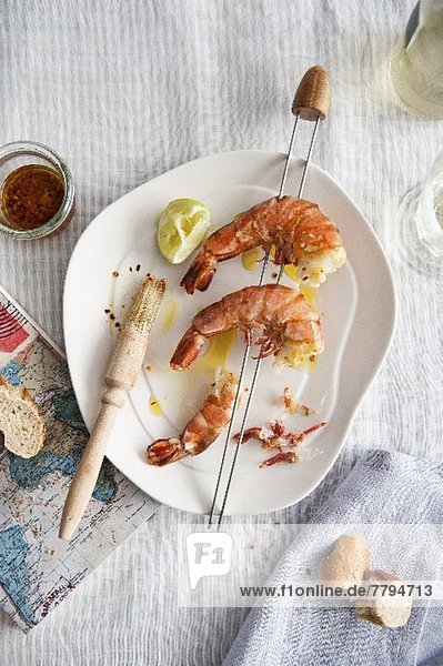 A king prawn skewer with bread and a map