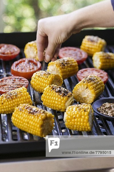 Corn on the cob being seasoned on the barbecue