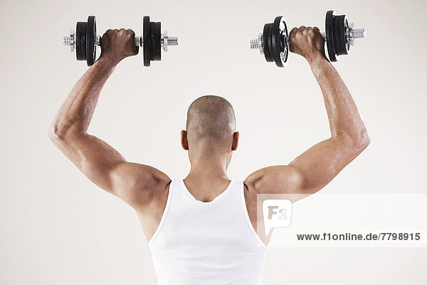 Man Wearing Work Out Clothes and Lifting Weights in Studio with White Background