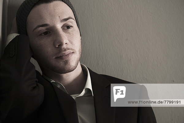 Portrait of Young Man wearing Woolen Hat and Suit Jacket  Looking to the Side  Absorbed in Thought  Studio Shot