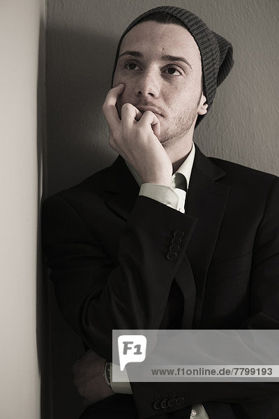 Portrait of Young Man wearing Woolen Hat and Suit Jacket  Looking Upward  Absorbed in Thought  Studio Shot