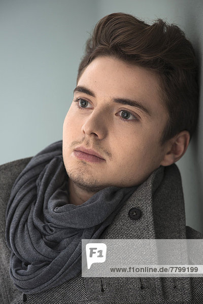 Head and Shoulder Portrait of Young Man wearing Grey Scarf and Jacket  Studio Shot on Grey Background