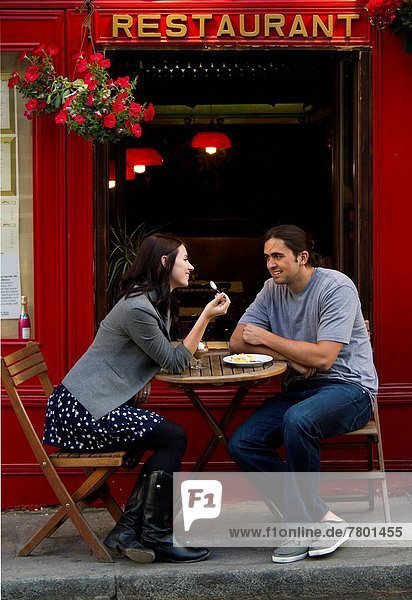 France Paris Young couple sitting in sidewalk cafe