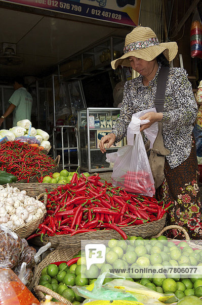 Frau kauft Chilischoten an einem Marktstand