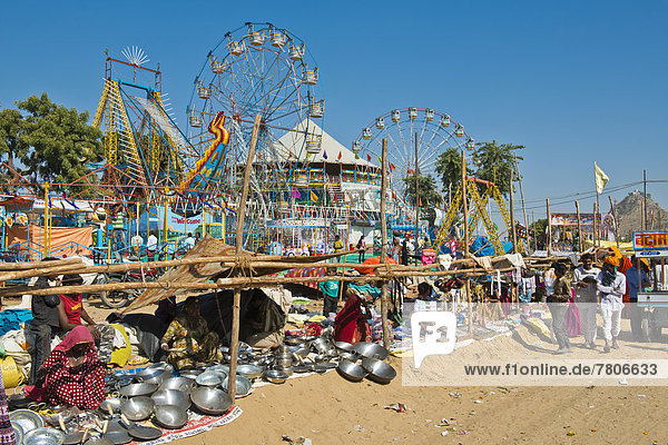 Stalls selling pots and Chapati pans  carnival with Ferris wheels at back  Pushkar Camel Fair