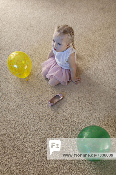 Kleines Mädchen zwischen zwei Luftballons als ihr Ballettschuh auf dem Boden liegt