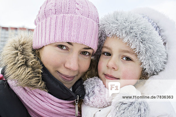 A mother and daughter in warm clothing outdoors in winter