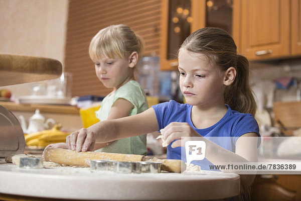 Two girls using baking dough