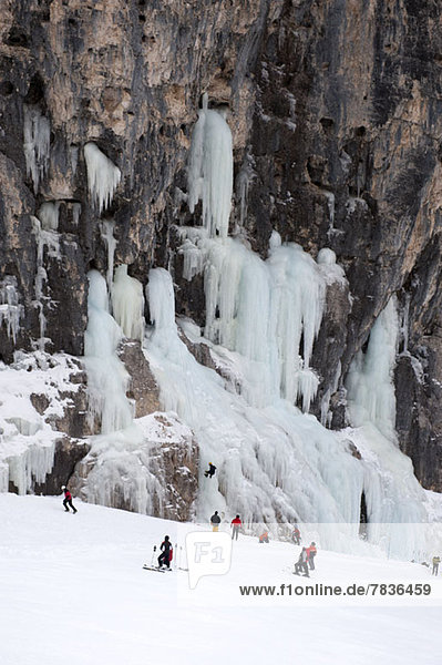 Skiers observe ice climber on rock face at Lagazuoi  South Tyrol  Italy